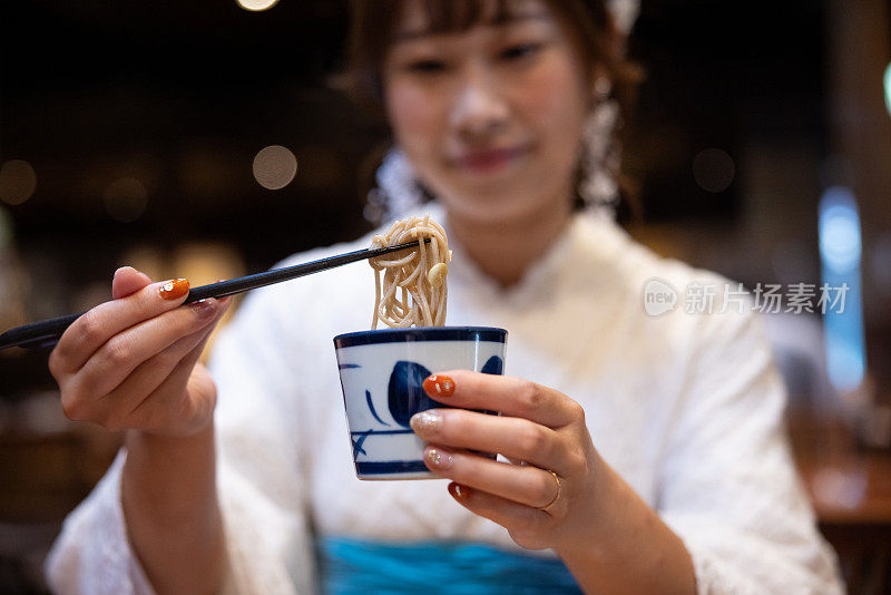 身着白色蕾丝和服的女子在日本餐厅吃荞麦面午餐