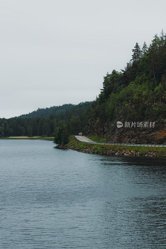 露营车行驶在公路上，可以看到瑞典的湖泊和森林的壮观景色