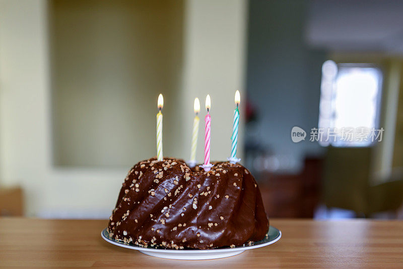 巧克力生日蛋糕和点燃的蜡烛在桌子上