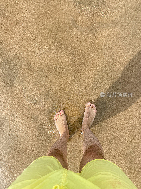 雄性的脚踩在沙滩上