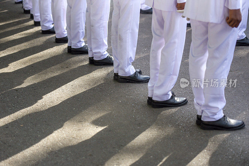 在白色服装和黑色鞋子的游行队伍中排队