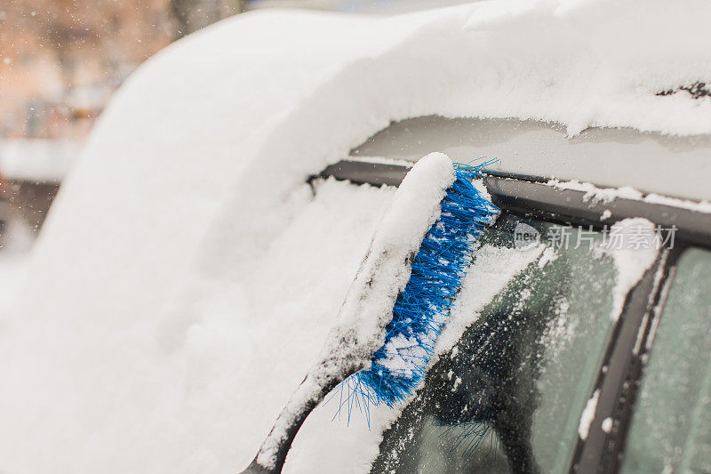 用刷子清理汽车上的积雪。雪下的汽车。冬天的天气。气候。风暴。运输
