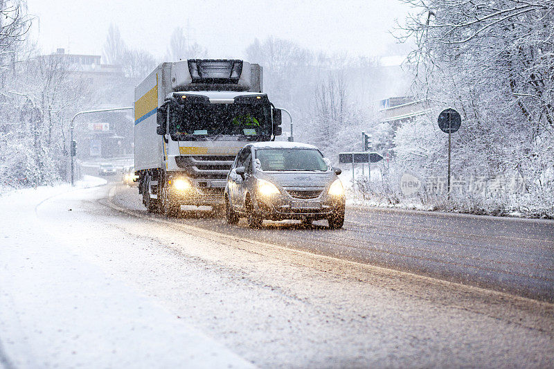 道路上的汽车和卡车在冬天的降雪中缓慢行驶