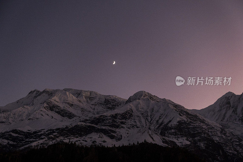 日落后美丽的山景和彩色的天空。日落后，山上浪漫的天空。白雪皑皑的山峰映衬着星空的背景。