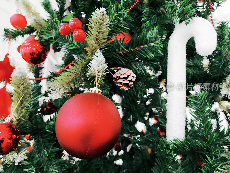 有装饰品、圣诞球和玩具的圣诞树。红白相间的挂饰。漂亮的球，明亮的浆果和球果。雪糖棒
