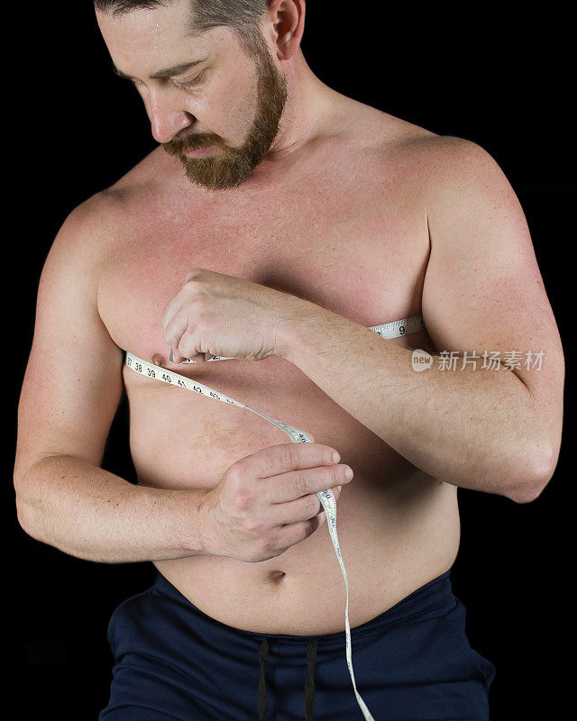 赤膊男子用卷尺测量他的胸部，看肌肉增加或体重减少的体脂百分比