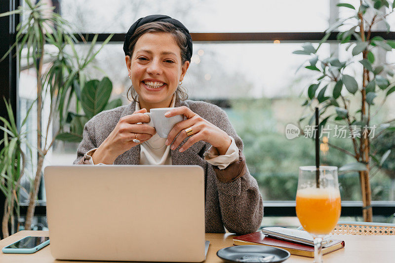 一位女士一边喝咖啡，一边用笔记本电脑进行视频会议或在线会议