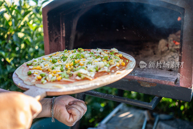 女人们把披萨放在石欧文的花园里，近距离观看家庭聚会