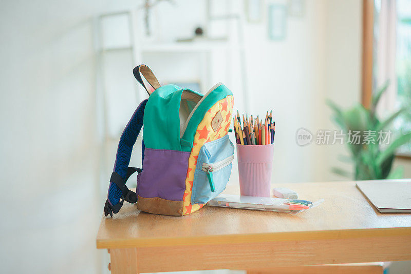 木凳上放着学校书包，背景是家