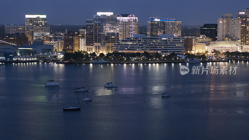 河畔市中心的夜光:伊丽莎白河上诺福克天际线的汽艇之旅。朴茨茅斯-诺福克，弗吉尼亚州方向。鸟瞰图