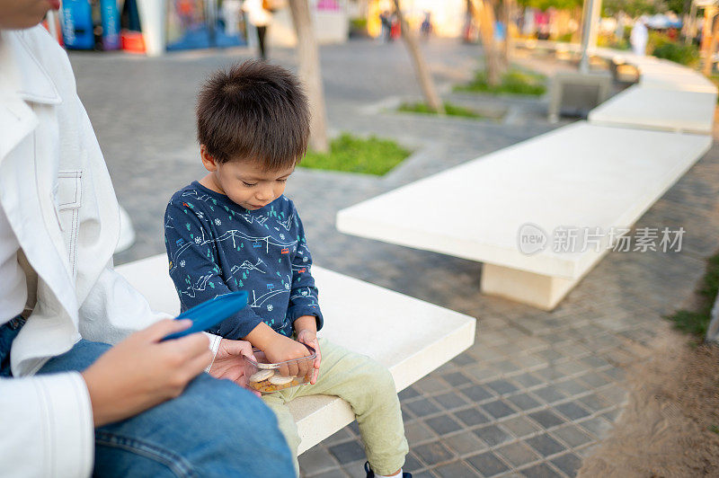 木板路上的甜蜜时刻:多种族小孩和妈妈一起享受零食