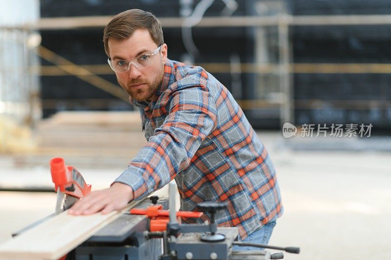 熟练的橱柜工在木工锯木厂用电动圆锯切割木板。专业橱柜制造商在锯木厂使用圆锯。木制家具生产。细木工