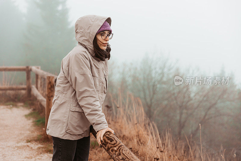 一个年轻的女性徒步旅行者在风和雾的肖像-股票照片