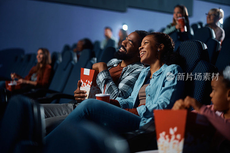 快乐的黑人夫妇在电影院享受电影放映。