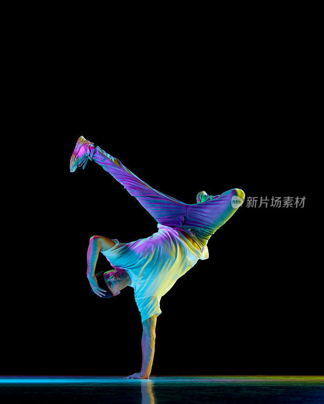 跳霹雳舞。年轻灵活的运动员在霓虹灯的黑色背景下，穿着运动服跳霹雳舞。