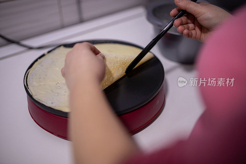 女人用锅铲在电煎锅上翻转煎饼