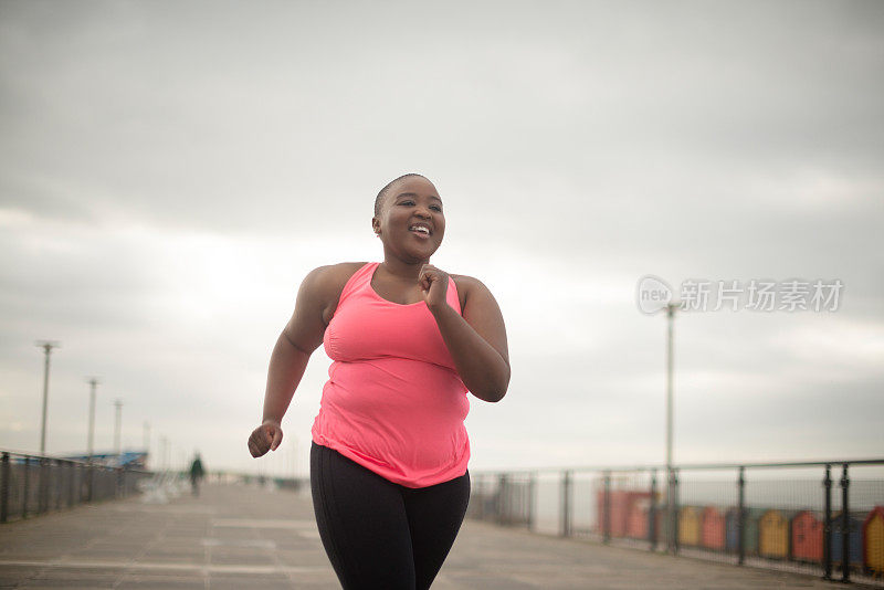 健身，微笑和加码黑人妇女早上在海滩散步，为健康，锻炼或有氧运动。马拉松，运动和快乐的年轻跑步者或运动员户外训练或锻炼
