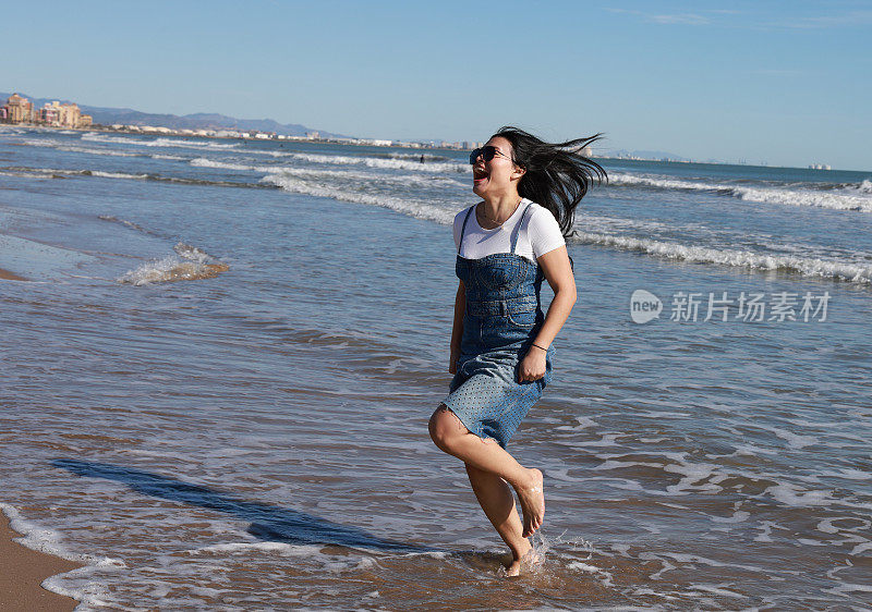 海滩上的年轻女士被冰冷的海水吓到了