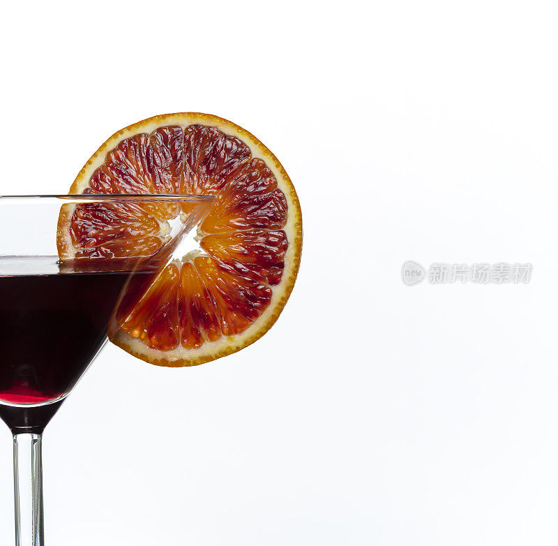 深紫色鸡尾酒杯与一片血橙隔离在白色背景。关闭了。