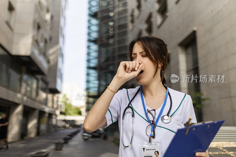 诊所里穿着制服的年轻女护士疲惫地打着哈欠