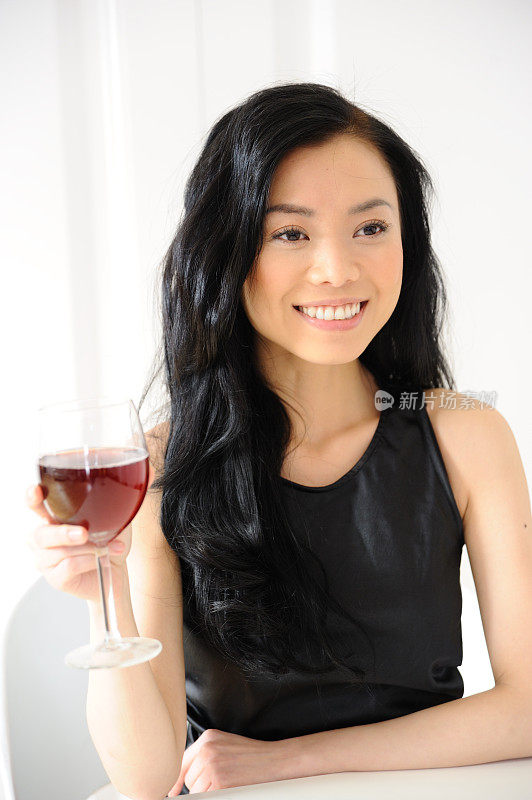 一个快乐的年轻亚洲女人拿着一个葡萄酒杯