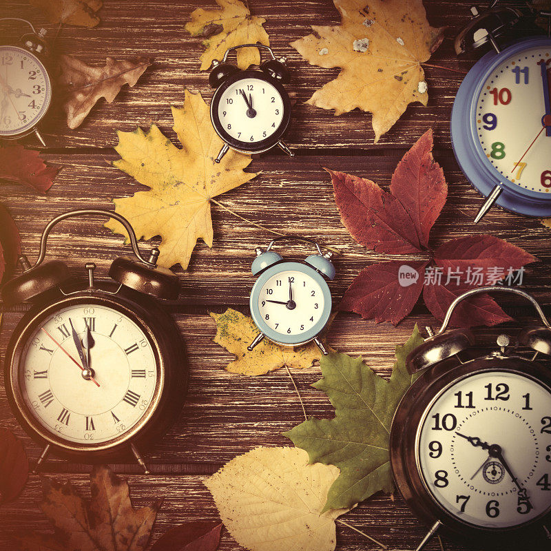 秋叶和闹钟放在木桌上。