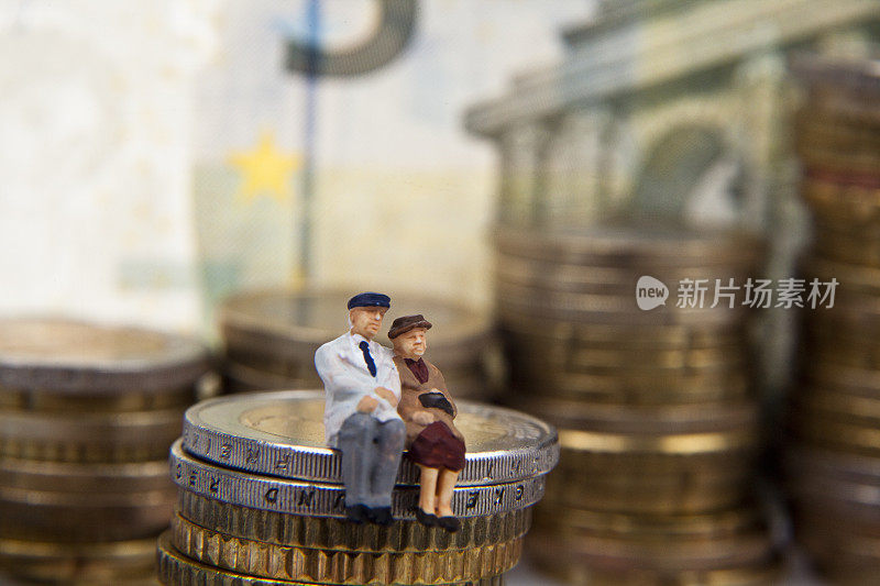一对老夫妇的小雕像放在一堆硬币上