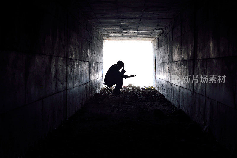一个悲伤的人坐在隧道里