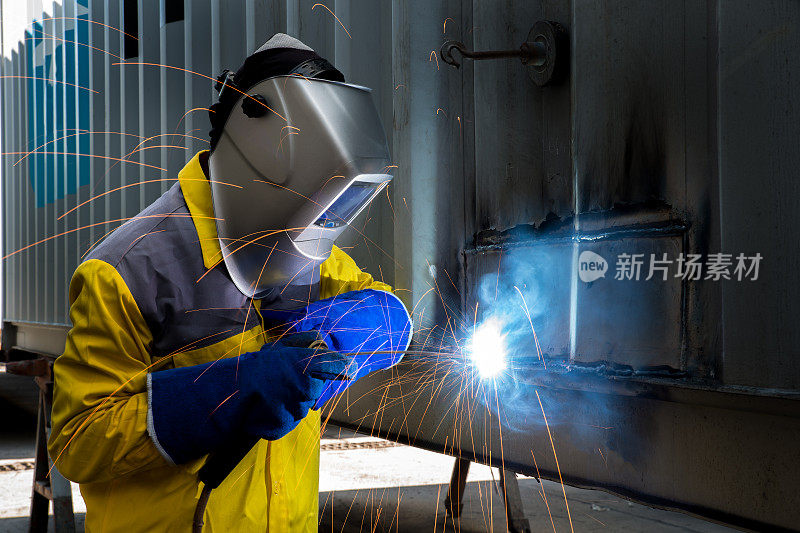 工业工人用焊接钢来修理集装箱