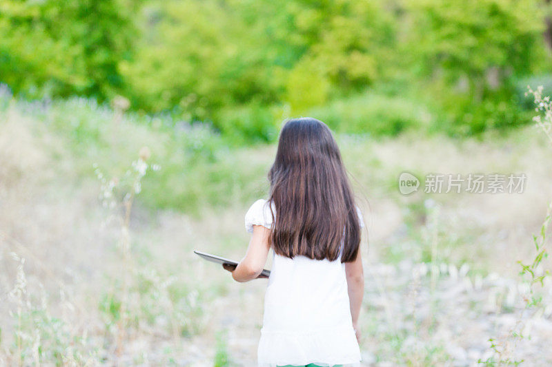 小女孩在树林里玩平板电脑