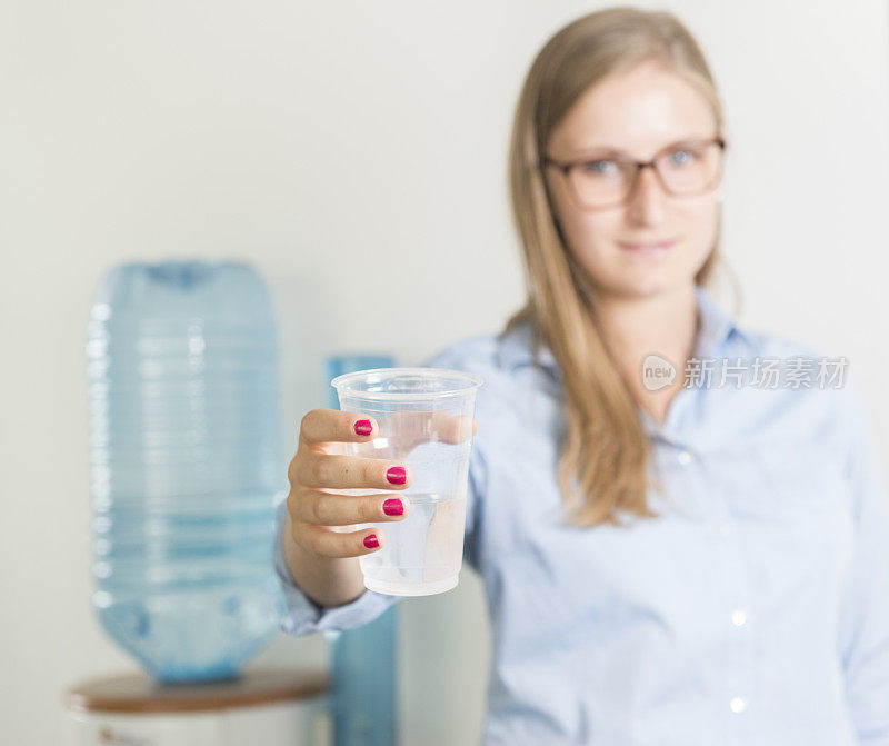 女商人用饮水机喝水。