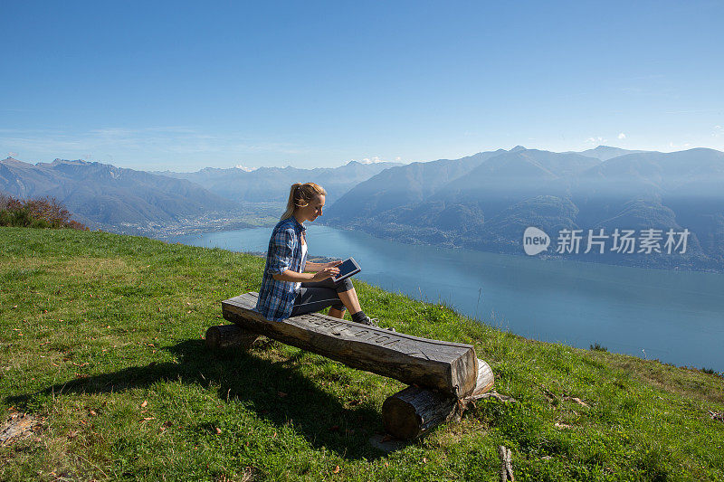 女人坐在长椅上，用着平板电脑