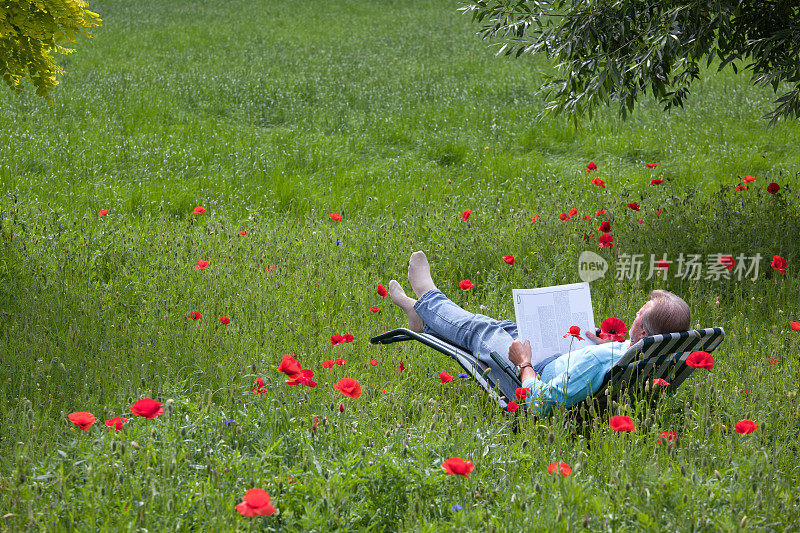 老人躺在花园的躺椅上看书