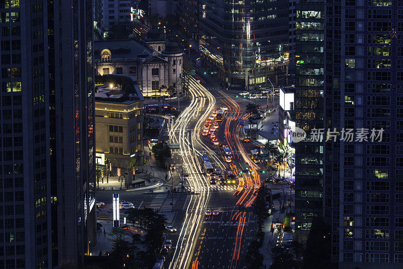 在韩国首尔的夜晚，摩天大楼间的车水马龙，霓虹闪烁