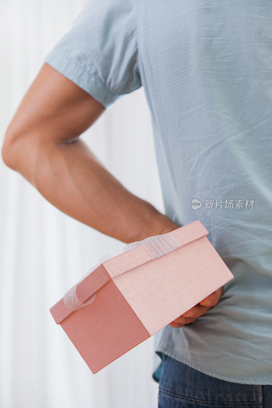 一个男人把粉红色的礼物藏在背后