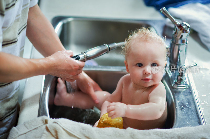 可爱的婴儿在厨房水槽里洗澡