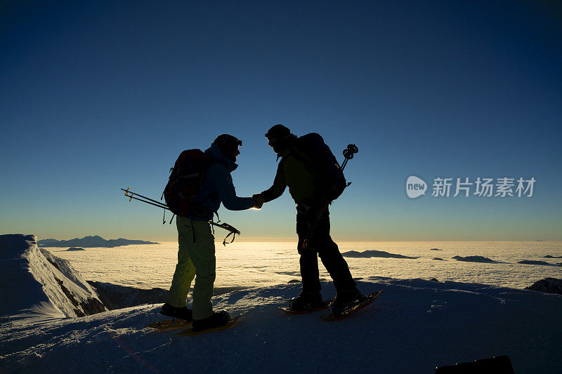 两个徒步旅行者在白雪覆盖的大地上握手