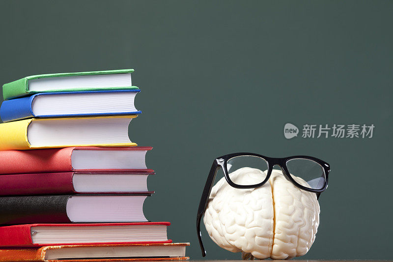 人的大脑和眼镜在黑板前的书本上