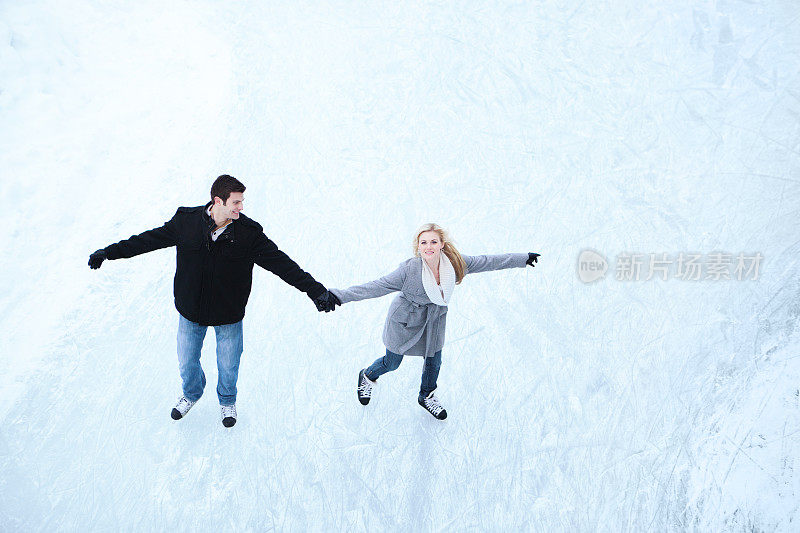 年轻浪漫的夫妇溜冰在冬季水平