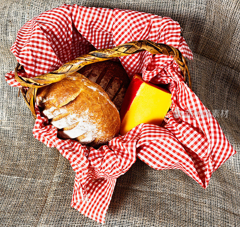 乡村野餐:面包和奶酪放在方格布的篮子里