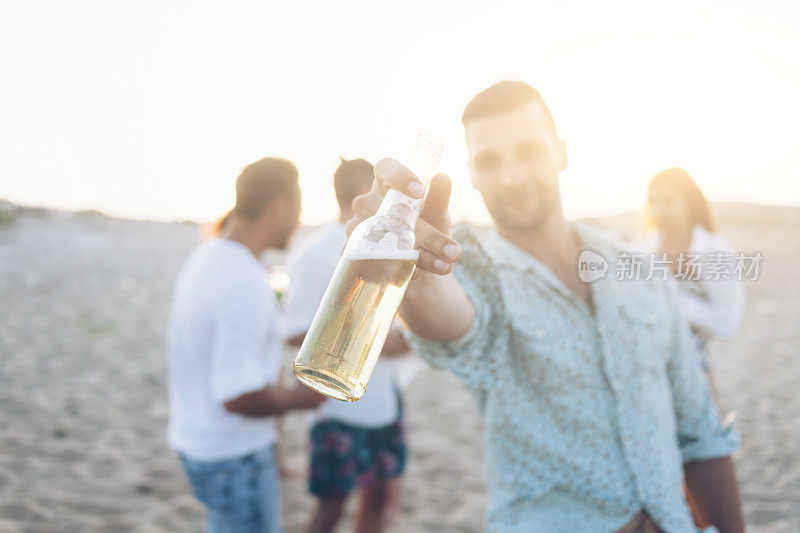 微笑的男人在海滩上用啤酒瓶欢呼