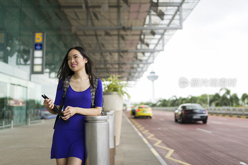 迷人的长发亚洲女人在机场候机厅外等候