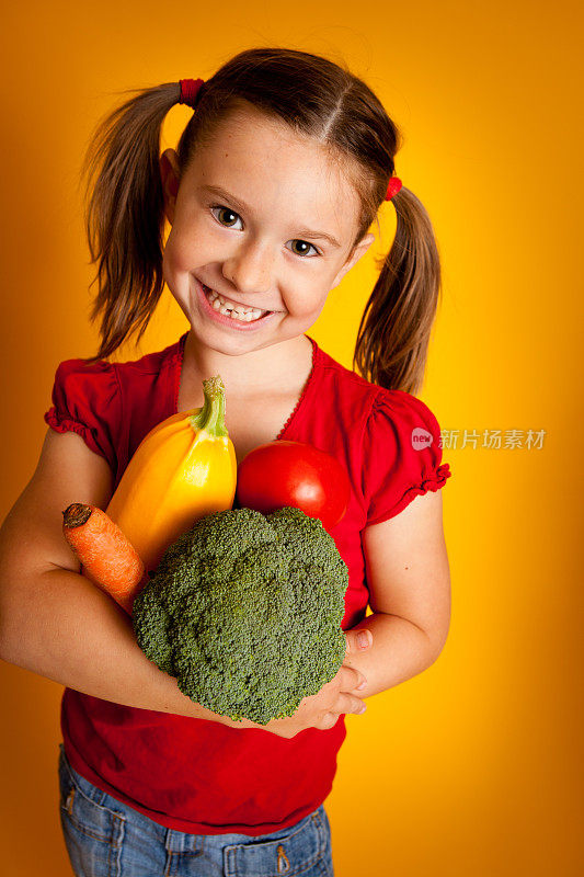 快乐的年轻女孩抱红灯笼椒，花椰菜，南瓜，胡萝卜