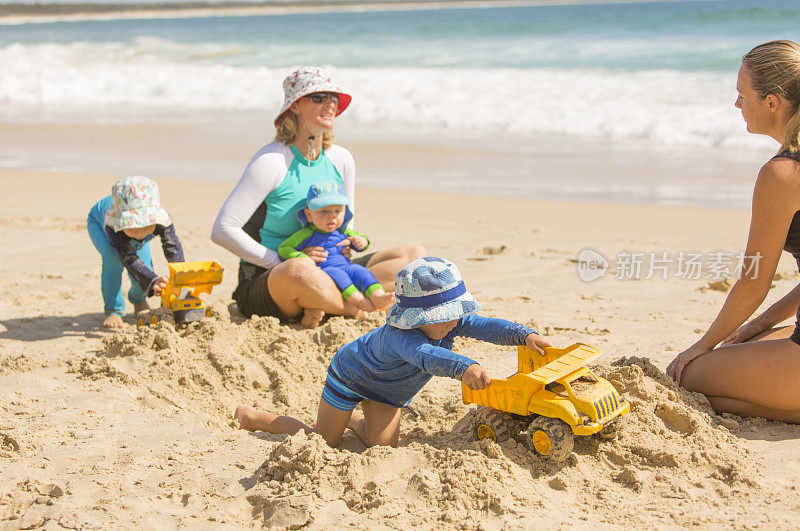 和妈妈一起在沙滩上挖沙子的男孩