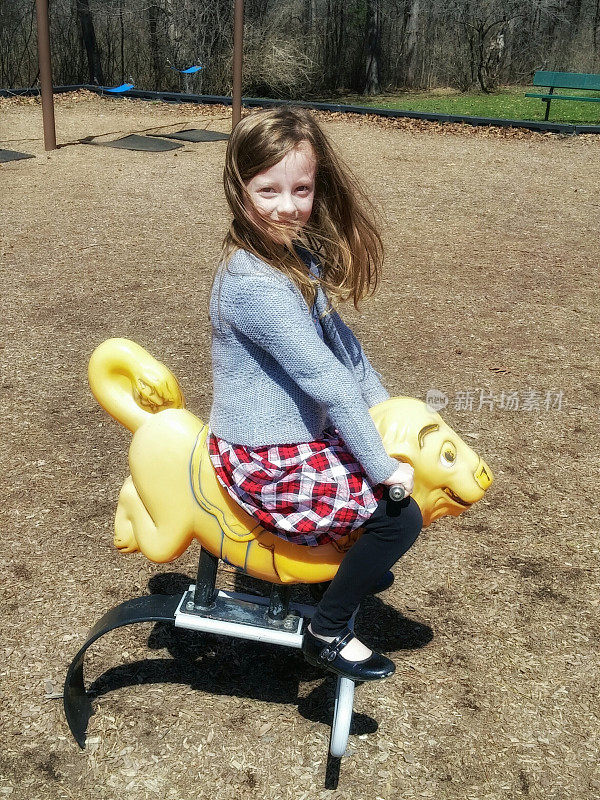 在游乐场公园玩春骑动物的女孩子