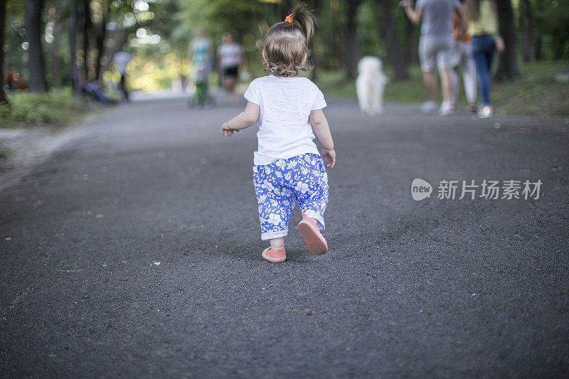 小女孩在公园里散步的后视图