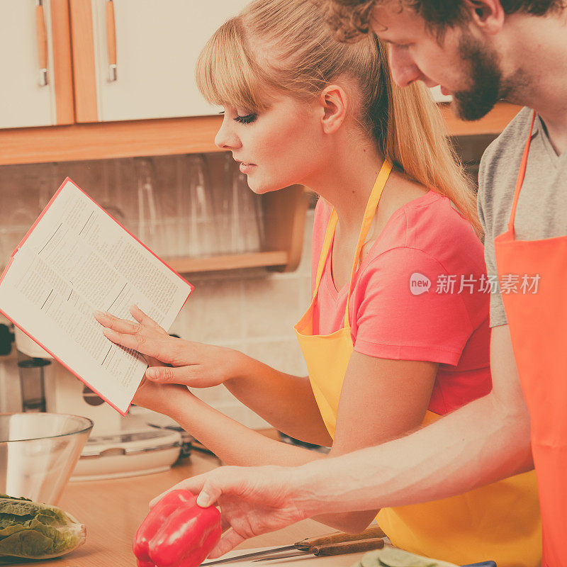 夫妇烹饪在厨房阅读食谱