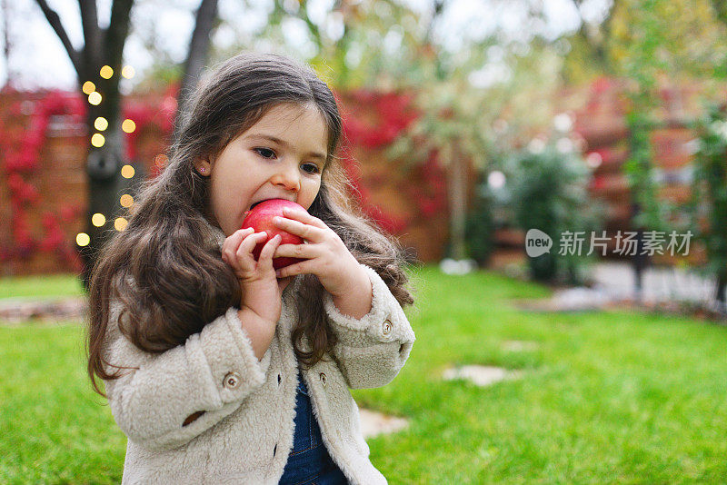 小女孩在花园里吃苹果