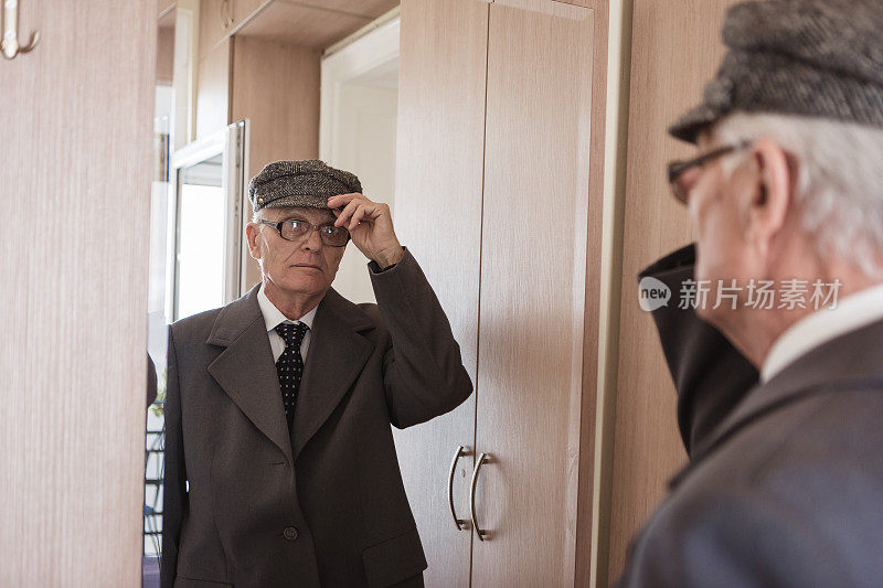 老年人在家里。老男人看着镜子，穿衣服