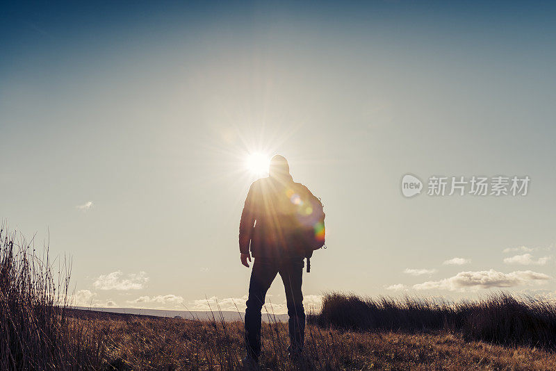 男人在秋日的阳光下徒步旅行。